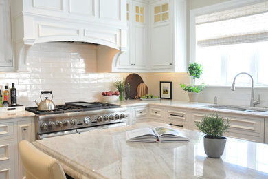Inspiration for a large transitional u-shaped medium tone wood floor and brown floor open concept kitchen remodel in Boston with an undermount sink, recessed-panel cabinets, white cabinets, marble countertops, white backsplash, ceramic backsplash, paneled appliances, an island and beige countertops
