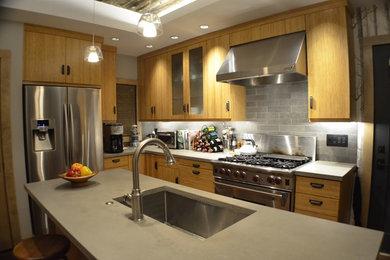 This is an example of a medium sized rustic l-shaped kitchen in Boston with a submerged sink, flat-panel cabinets, grey cabinets, concrete worktops, grey splashback, metro tiled splashback, stainless steel appliances, medium hardwood flooring, an island and brown floors.