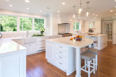 Kitchen pantry - huge transitional u-shaped medium tone wood floor and brown floor kitchen pantry idea in Richmond with a farmhouse sink, beaded inset cabinets, white cabinets, quartz countertops, white backsplash, subway tile backsplash, stainless steel appliances, two islands and white countertops