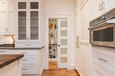 ポートランド(メイン)にあるラグジュアリーな広いおしゃれなキッチン (シェーカースタイル扉のキャビネット、白いキャビネット、木材カウンター、シルバーの調理設備、無垢フローリング) の写真