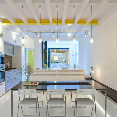 Large minimalist single-wall white floor eat-in kitchen photo in London with flat-panel cabinets, white cabinets, stainless steel appliances and an island