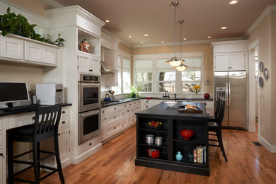 Example of a mid-sized classic l-shaped light wood floor eat-in kitchen design in Denver with shaker cabinets, white cabinets, soapstone countertops, white backsplash, subway tile backsplash, stainless steel appliances, a drop-in sink and an island