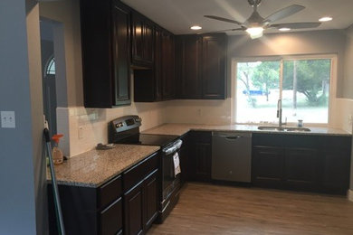 Medium sized classic l-shaped kitchen/diner in Austin with a double-bowl sink, raised-panel cabinets, dark wood cabinets, stainless steel appliances, medium hardwood flooring and no island.