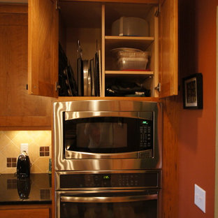 Photo of an arts and crafts l-shaped eat-in kitchen in Chicago with an undermount sink, shaker cabinets, medium wood cabinets, granite benchtops, beige splashback, stone tile splashback and stainless steel appliances.