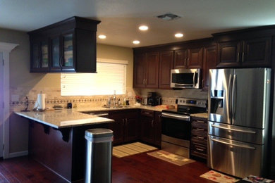 Example of a mid-sized classic u-shaped dark wood floor eat-in kitchen design in Sacramento with a peninsula, raised-panel cabinets, dark wood cabinets, granite countertops, beige backsplash, mosaic tile backsplash, stainless steel appliances and an undermount sink