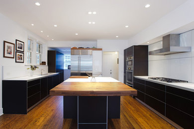 Eat-in kitchen - modern u-shaped medium tone wood floor eat-in kitchen idea in Chicago with an undermount sink, flat-panel cabinets, brown cabinets, laminate countertops, yellow backsplash, glass sheet backsplash, stainless steel appliances and an island