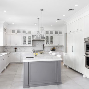 Inspiration for a large transitional u-shaped separate kitchen in New York with an undermount sink, recessed-panel cabinets, white cabinets, marble benchtops, white splashback, marble splashback, stainless steel appliances, marble floors, with island, grey floor and white benchtop.