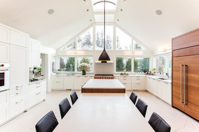 Example of a transitional u-shaped beige floor kitchen design in New York with an undermount sink, shaker cabinets, white cabinets, paneled appliances, two islands and white countertops