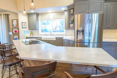 Inspiration for an eclectic single-wall porcelain tile open concept kitchen remodel in Denver with a farmhouse sink, raised-panel cabinets, gray cabinets, quartzite countertops, multicolored backsplash, ceramic backsplash, stainless steel appliances and an island