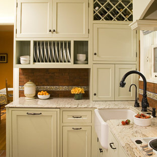 This is an example of a traditional kitchen in Seattle with a farmhouse sink, beaded inset cabinets, green cabinets, granite benchtops, red splashback and terra-cotta splashback.