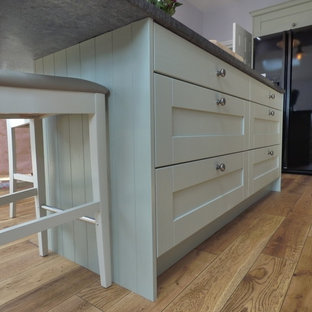 Design ideas for a large eclectic u-shaped open plan kitchen in Other with a farmhouse sink, shaker cabinets, green cabinets, granite benchtops, black splashback, mosaic tile splashback, black appliances, medium hardwood floors and with island.