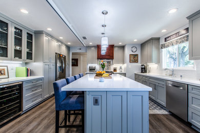 Example of a mid-sized minimalist u-shaped vinyl floor and brown floor open concept kitchen design in Sacramento with an undermount sink, shaker cabinets, gray cabinets, quartzite countertops, white backsplash, ceramic backsplash, stainless steel appliances, an island and white countertops