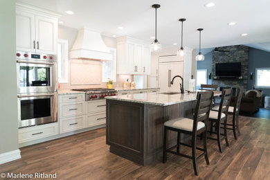 Large transitional l-shaped medium tone wood floor and brown floor eat-in kitchen photo in New York with an undermount sink, recessed-panel cabinets, beige cabinets, granite countertops, beige backsplash, subway tile backsplash, stainless steel appliances, an island and beige countertops