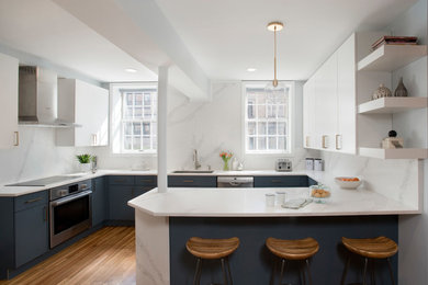 Contemporary u-shaped kitchen/diner in Boston with a submerged sink, flat-panel cabinets, blue cabinets, engineered stone countertops, white splashback, stainless steel appliances, medium hardwood flooring, a breakfast bar, white worktops and brown floors.