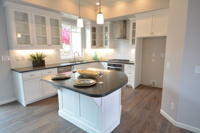 Mid-sized elegant l-shaped dark wood floor and brown floor kitchen photo in San Diego with an undermount sink, shaker cabinets, white cabinets, solid surface countertops, white backsplash, subway tile backsplash, stainless steel appliances and an island