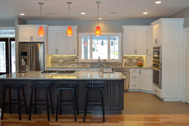 Transitional l-shaped porcelain tile kitchen photo in Boston with an undermount sink, raised-panel cabinets, white cabinets, quartz countertops, multicolored backsplash, mosaic tile backsplash, stainless steel appliances and an island