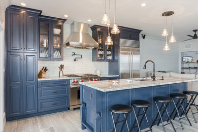 Exempel på ett maritimt linjärt kök och matrum, med luckor med upphöjd panel, blå skåp, granitbänkskiva, vitt stänkskydd, rostfria vitvaror och en köksö