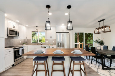 Inspiration for a mid-sized contemporary l-shaped vinyl floor and gray floor open concept kitchen remodel in Seattle with an undermount sink, shaker cabinets, white cabinets, quartz countertops, gray backsplash, ceramic backsplash, stainless steel appliances, an island and white countertops