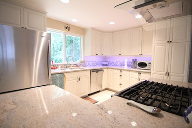 Example of a mid-sized trendy l-shaped terra-cotta tile eat-in kitchen design in Seattle with a double-bowl sink, raised-panel cabinets, white cabinets, granite countertops, multicolored backsplash, glass tile backsplash, stainless steel appliances and an island