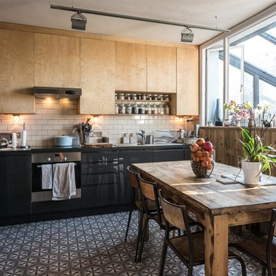 Inspiration for a contemporary l-shaped eat-in kitchen remodel in Sussex with flat-panel cabinets, beige backsplash, subway tile backsplash, stainless steel appliances and no island