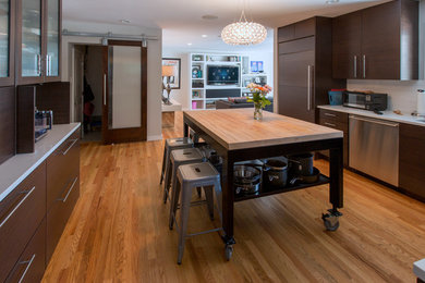 Photo of a contemporary open plan kitchen in DC Metro with flat-panel cabinets, dark wood cabinets, white splashback, stainless steel appliances, medium hardwood flooring and an island.