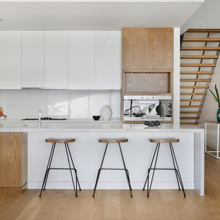 Design ideas for a large contemporary galley kitchen in Melbourne with an undermount sink, white cabinets, quartz benchtops, grey splashback, stone slab splashback, stainless steel appliances, light hardwood floors, with island, beige floor, flat-panel cabinets and grey benchtop.