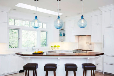 Example of a large transitional l-shaped slate floor open concept kitchen design in San Francisco with a farmhouse sink, shaker cabinets, white cabinets, wood countertops, multicolored backsplash, paneled appliances and an island