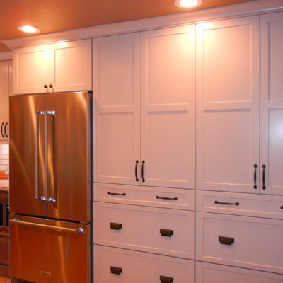 Example of a mid-sized country u-shaped ceramic tile and multicolored floor eat-in kitchen design in Orange County with a farmhouse sink, shaker cabinets, white cabinets, quartz countertops, white backsplash, ceramic backsplash, stainless steel appliances, no island and white countertops