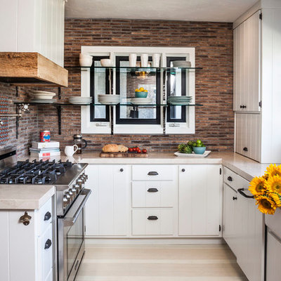 Enclosed kitchen - eclectic u-shaped enclosed kitchen idea in Orange County with marble countertops, a farmhouse sink, white cabinets, stainless steel appliances, multicolored backsplash and beige countertops
