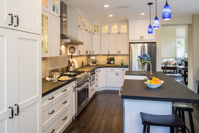 Example of a classic l-shaped eat-in kitchen design in San Diego with a drop-in sink, recessed-panel cabinets, white cabinets, solid surface countertops, beige backsplash, subway tile backsplash and stainless steel appliances