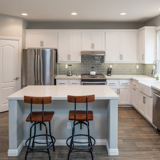 Inspiration for a mid-sized modern u-shaped kitchen in San Diego with a farmhouse sink, shaker cabinets, white cabinets, quartz benchtops, grey splashback, subway tile splashback, stainless steel appliances, plywood floors and with island.