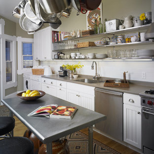 Inspiration for a mid-sized eclectic galley eat-in kitchen in San Francisco with subway tile splashback, a drop-in sink, beaded inset cabinets, white cabinets, white splashback, stainless steel appliances, light hardwood floors, with island and solid surface benchtops.