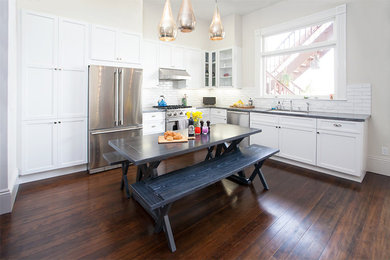 Example of a mid-sized trendy l-shaped dark wood floor open concept kitchen design in San Francisco with an undermount sink, shaker cabinets, white cabinets, soapstone countertops, white backsplash, ceramic backsplash, stainless steel appliances and no island