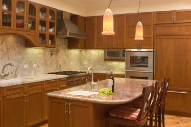 Example of a large transitional l-shaped light wood floor and brown floor kitchen design in San Francisco with granite countertops, paneled appliances, an undermount sink, shaker cabinets, medium tone wood cabinets, multicolored backsplash, stone slab backsplash and an island