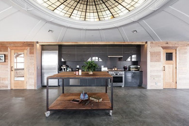 Inspiration for a mid-sized modern single-wall concrete floor and gray floor open concept kitchen remodel in San Francisco with an undermount sink, flat-panel cabinets, gray cabinets, solid surface countertops, gray backsplash, cement tile backsplash, stainless steel appliances and an island
