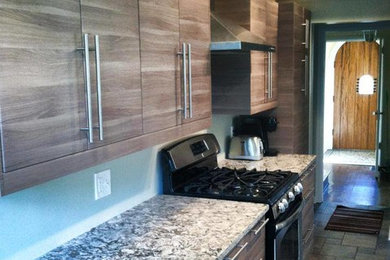 Cette image montre une petite cuisine parallèle minimaliste en bois clair fermée avec un évier encastré, un placard à porte plane, un plan de travail en quartz modifié, un électroménager en acier inoxydable, un sol en ardoise et une péninsule.