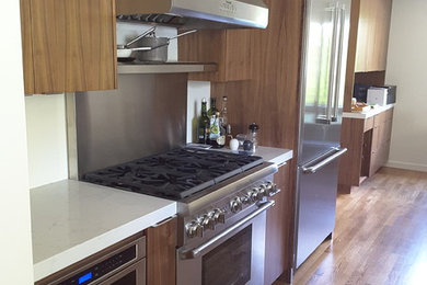 サクラメントにある中くらいなコンテンポラリースタイルのおしゃれなキッチン (フラットパネル扉のキャビネット、中間色木目調キャビネット、シルバーの調理設備、無垢フローリング) の写真