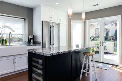Enclosed kitchen - small transitional l-shaped medium tone wood floor enclosed kitchen idea in San Francisco with a farmhouse sink, shaker cabinets, white cabinets, granite countertops, gray backsplash, stone slab backsplash, stainless steel appliances and an island