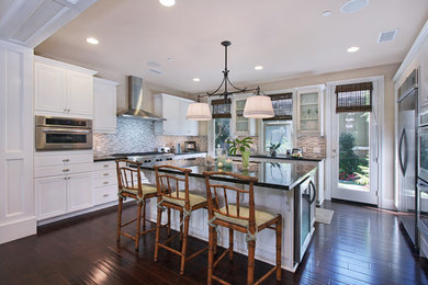 Open concept kitchen - large coastal single-wall dark wood floor open concept kitchen idea in Orange County with a double-bowl sink, recessed-panel cabinets, white cabinets, granite countertops, gray backsplash, mosaic tile backsplash, stainless steel appliances and an island