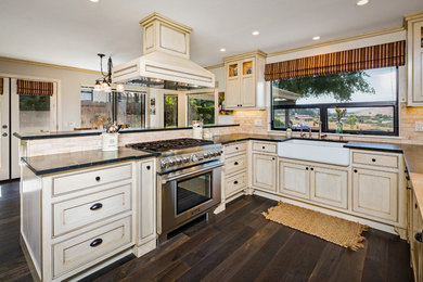 Example of a large classic u-shaped dark wood floor and brown floor eat-in kitchen design in San Luis Obispo with a farmhouse sink, shaker cabinets, light wood cabinets, soapstone countertops, stainless steel appliances and a peninsula