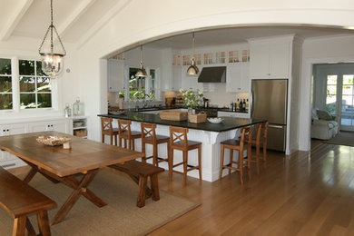 Example of a mid-sized beach style u-shaped light wood floor open concept kitchen design in Santa Barbara with an undermount sink, recessed-panel cabinets, white cabinets, soapstone countertops, white backsplash, subway tile backsplash and stainless steel appliances