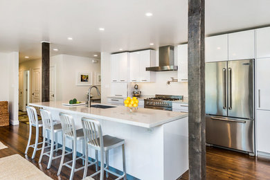 Large minimalist single-wall dark wood floor and brown floor open concept kitchen photo in San Francisco with an undermount sink, stainless steel appliances, flat-panel cabinets, white cabinets, quartz countertops, white backsplash, stone slab backsplash, an island and white countertops