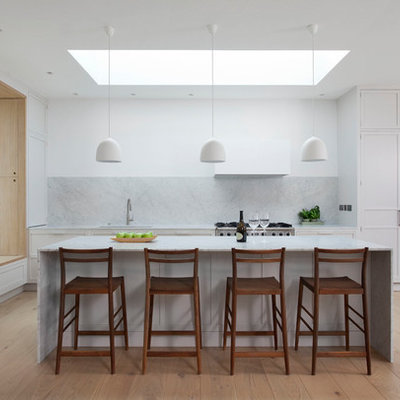 Mid-sized trendy beige floor and light wood floor open concept kitchen photo in Dublin with recessed-panel cabinets, white cabinets, marble countertops, gray backsplash, marble backsplash, an island, gray countertops and stainless steel appliances