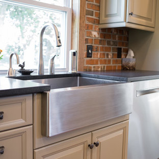 Large farmhouse eat-in kitchen designs - Inspiration for a large cottage single-wall medium tone wood floor and brown floor eat-in kitchen remodel in Philadelphia with a farmhouse sink, raised-panel cabinets, beige cabinets, soapstone countertops, red backsplash, brick backsplash, stainless steel appliances and an island