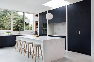 Photo of a contemporary l-shaped open plan kitchen in Other with flat-panel cabinets, blue cabinets, marble worktops, white splashback, marble splashback, black appliances, concrete flooring, an island, grey floors and white worktops.
