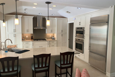 Inspiration for a mid-sized transitional beige floor eat-in kitchen remodel in Miami with an undermount sink, white cabinets, brown backsplash, stainless steel appliances, an island, beige countertops, flat-panel cabinets, quartz countertops and glass tile backsplash