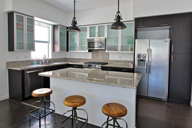Example of a minimalist porcelain tile kitchen design in Orange County with glass-front cabinets, stainless steel cabinets, granite countertops, stainless steel appliances and an island