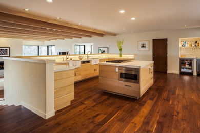 Example of a large trendy u-shaped dark wood floor open concept kitchen design in Santa Barbara with a farmhouse sink, flat-panel cabinets, light wood cabinets, granite countertops, white backsplash, stone slab backsplash, stainless steel appliances and an island