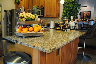 Inspiration for a mid-sized timeless l-shaped ceramic tile eat-in kitchen remodel in New Orleans with an undermount sink, louvered cabinets, light wood cabinets, granite countertops, beige backsplash, stone tile backsplash, stainless steel appliances and a peninsula