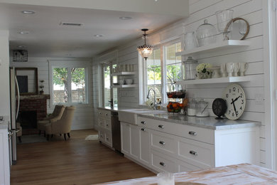 Example of a mid-sized classic laminate floor kitchen design in Los Angeles with a farmhouse sink, shaker cabinets, white cabinets, marble countertops, white backsplash, subway tile backsplash and stainless steel appliances